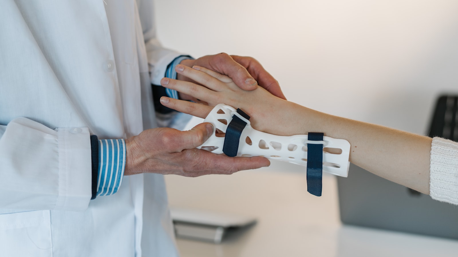 A clinician fitting a wrist splint onto a patient's forearm.