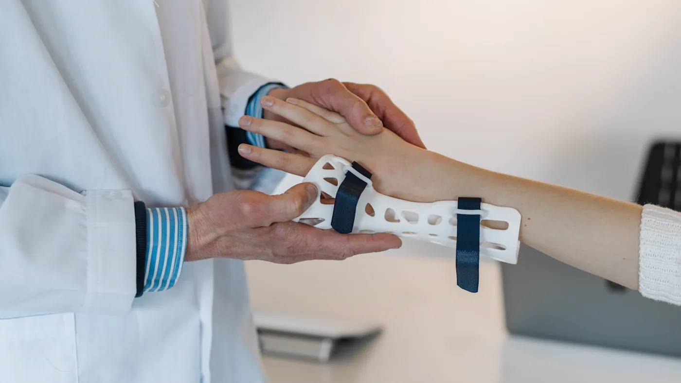 A clinician fitting a wrist splint onto a patient's forearm.