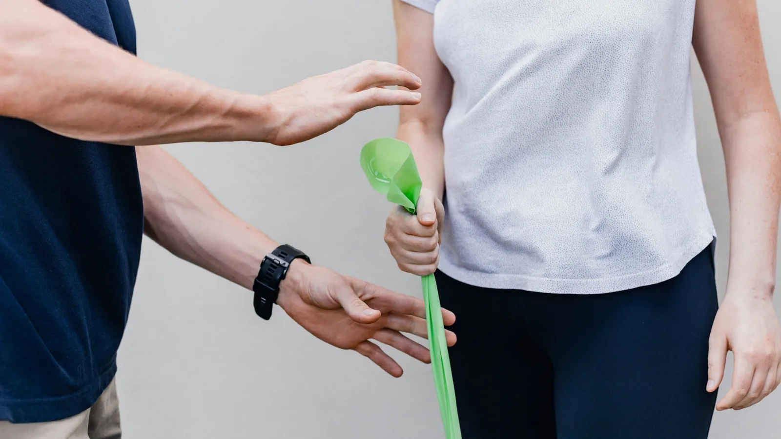 A physical therapist guiding a patient through a resistance-band exercise in a clinic.